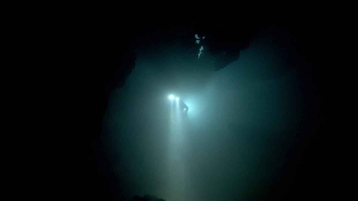 A diver floats through an underwater cave. 