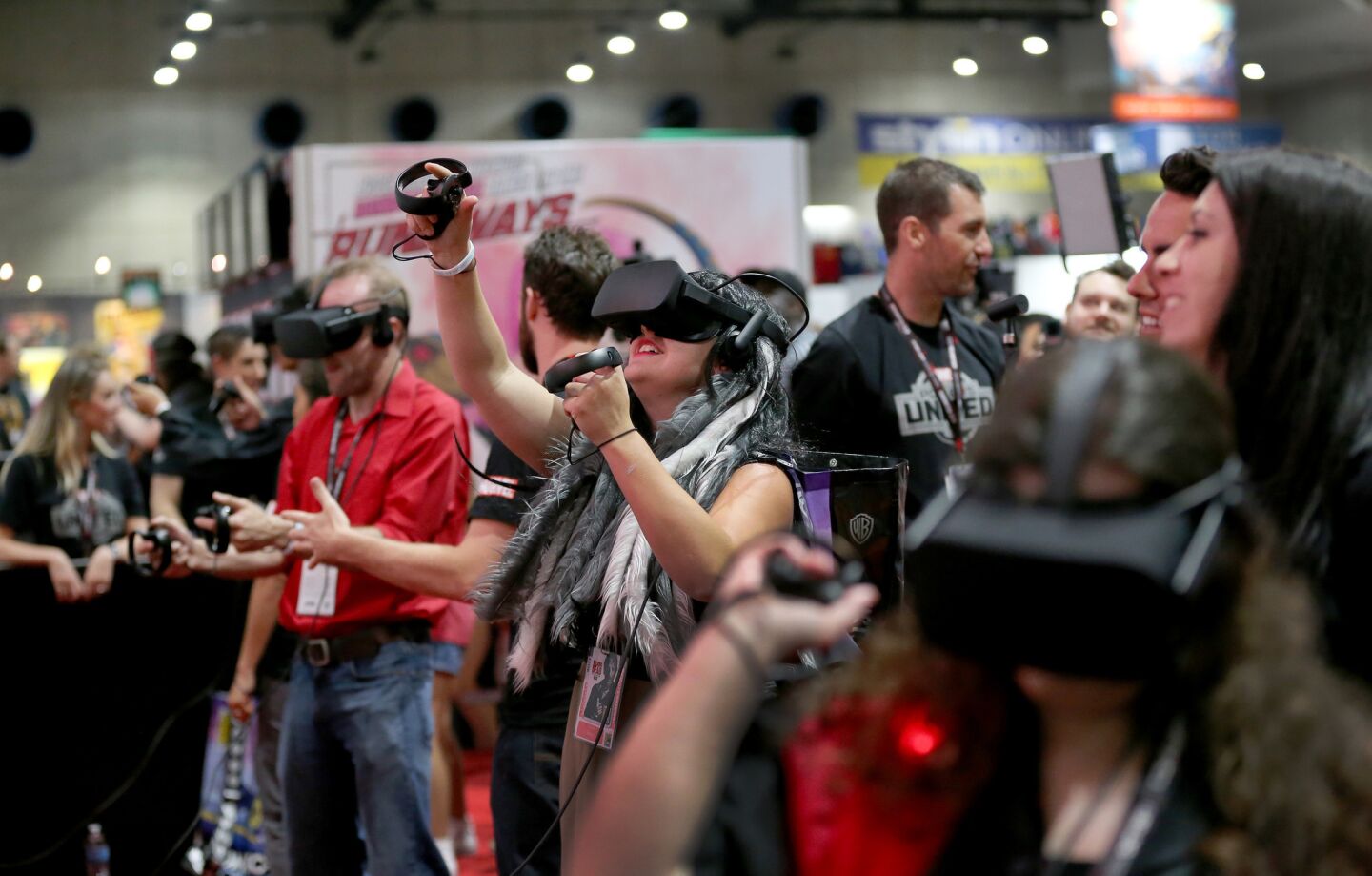 Kendra Abbott, center, of San Diego joins fellow virtual reality players competing using the Oculus Rift VR headset with touch controllers and the Marvel Powers United VR (due out next year) during the preview night opener at Comic Con.