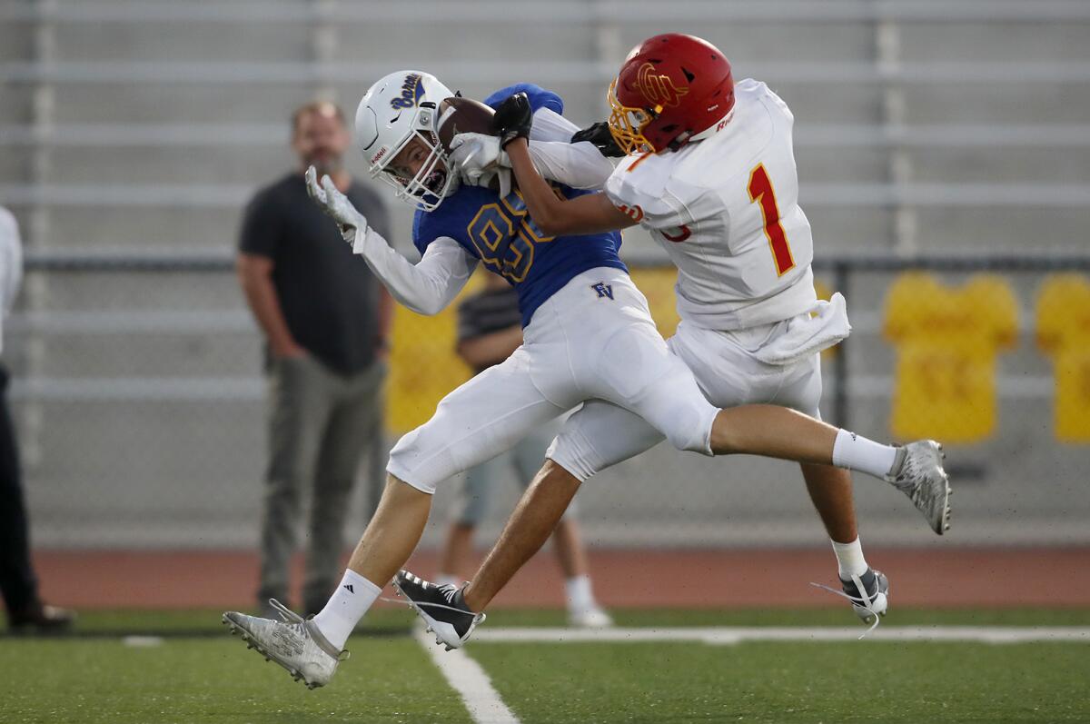 Fountain Valley wide receiver Blake Anderson, left, holds on to complete the 43-yard reception against Woodbridge's Vincent Garcia in the first half of a nonleague game on Thursday at Huntington Beach High.