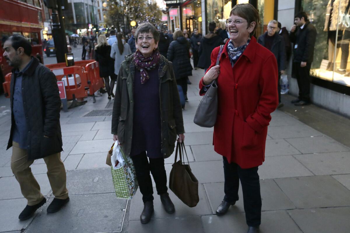 Two sisters pose for a photograph as they walk down Oxford Street in London on Dec. 9.