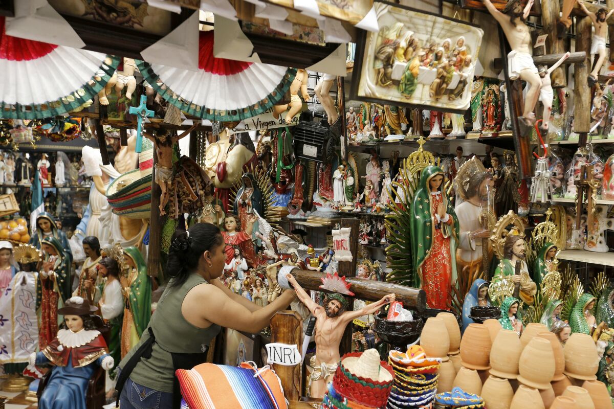 A worker displays Christian figures at her stall at El Mercado in Boyle Heights. El Mercado has been around since 1968 and largely serves the Latino immigrant community in Boyle Heights.
