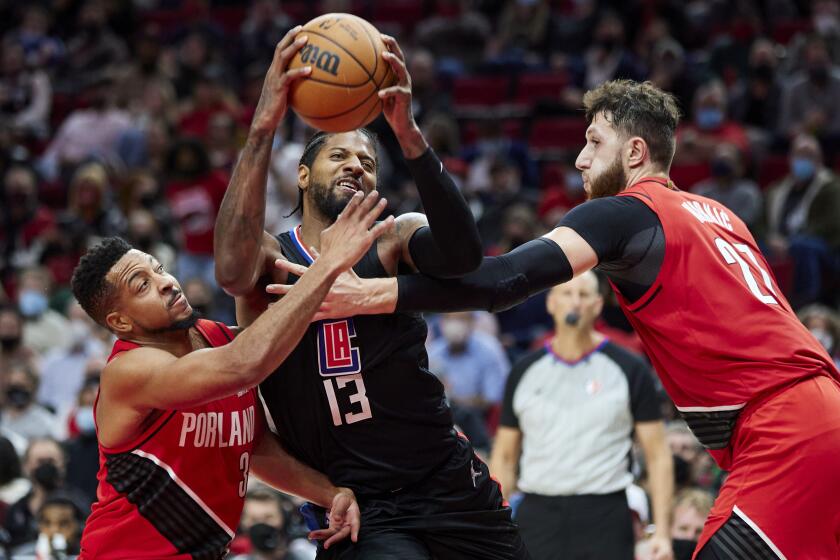 Los Angeles Clippers guard Paul George drives to the basket between Portland Trail Blazers guard CJ McCollum, left, and center Jusuf Nurkic during the second half of an NBA basketball game in Portland, Ore., Friday, Oct. 29, 2021. (AP Photo/Craig Mitchelldyer)