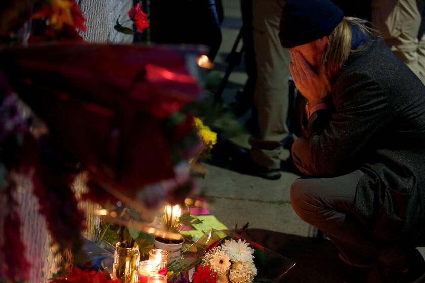 A man who identified himself as Ben P reads the cards at a makeshift memorial on Sunday near the site of the warehouse fire in Oakland.