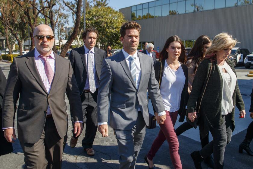 NEWPORT BEACH, CALIF. -- FRIDAY, FEBRUARY 7, 2020: Philip Cohen, left, defense attorney for Robicheaux, Newport Beach surgeon Grant Robicheaux, center, and his girlfriend Cerissa Riley leave the Harbor Justice Center where Judge Gregory Jones delayed dismissing rape charges against the doctor and girlfriend, saying politics has ‘infected this case’ in Newport Beach, Calif., on Feb. 7, 2020. (Allen J. Schaben / Los Angeles Times)