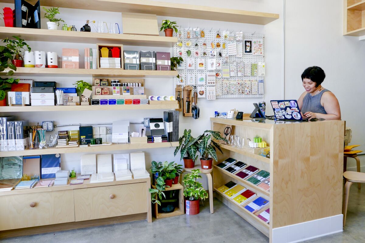 Paper products on shelves and a woman behind a counter.