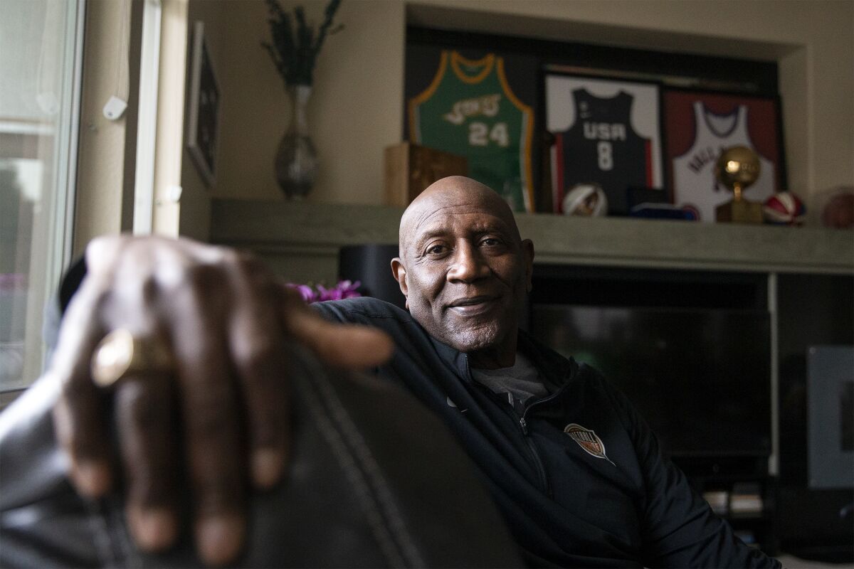 Former professional basketball player and Olympic gold medalist Spencer Haywood poses for a photo in front of his basketball memorabilia at his Las Vegas home Monday, Nov. 29, 2021. Haywood, the trailblazing forward who grew up picking cotton in Mississippi and wound up reshaping the league in a way that many take for granted today. (AP Photo/Ellen Schmidt)