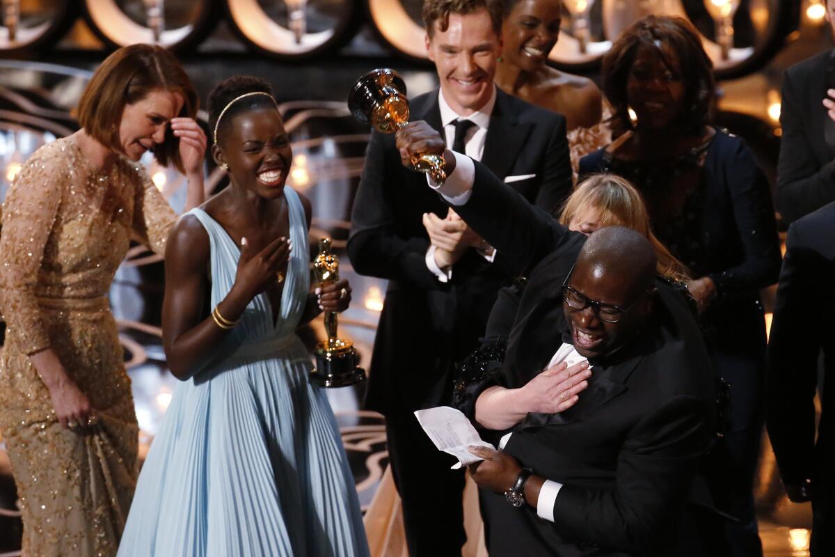Director Steve McQueen thrusts his fist in elation as he celebrates winning the Oscar for best picture with cast and crew from "12 Years a Slave."
