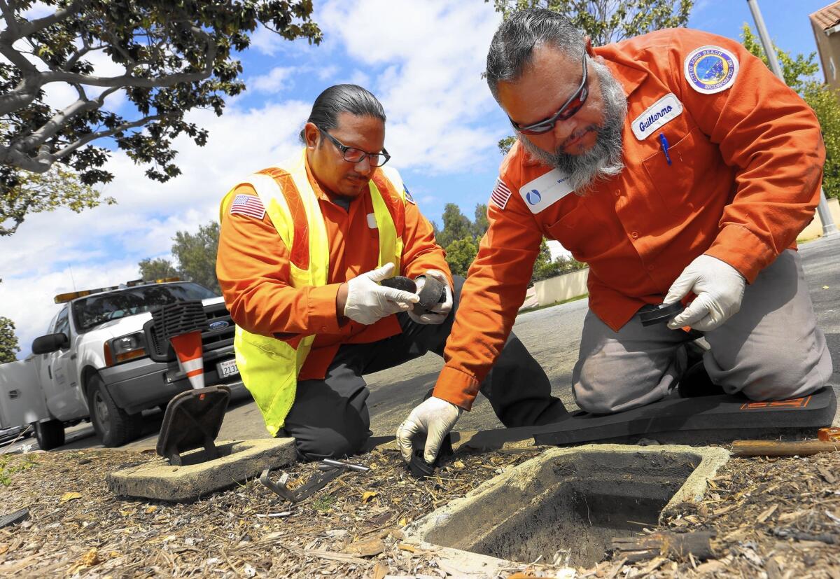 City of Long Beach workers Jared Mataalii, left, and Guillermo Lopez remove a water meter in order to install a "smart meter."