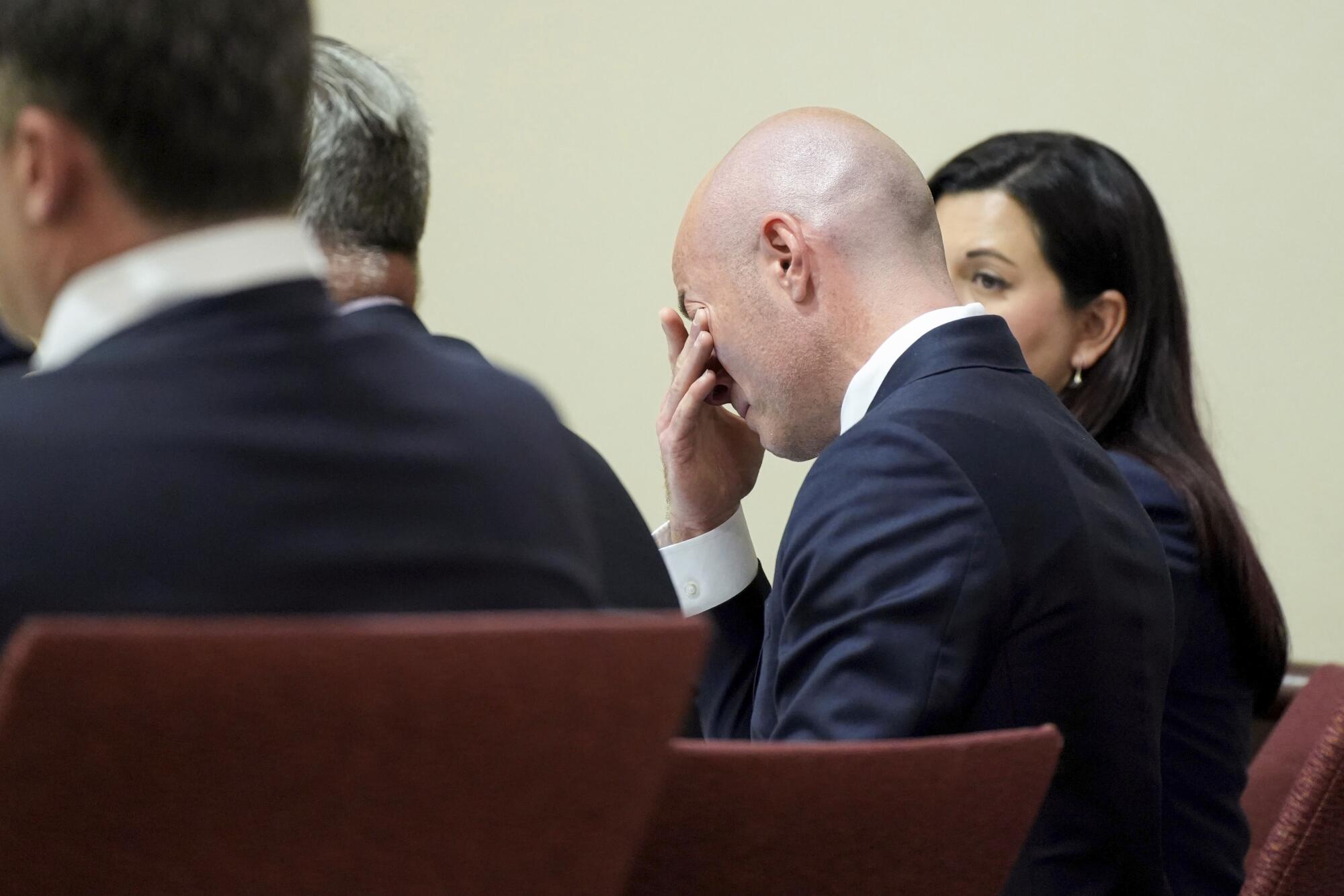 Attorney Luke Nikas rubs his eyes during actor Alec Baldwin's trial while other people are seated next to him.