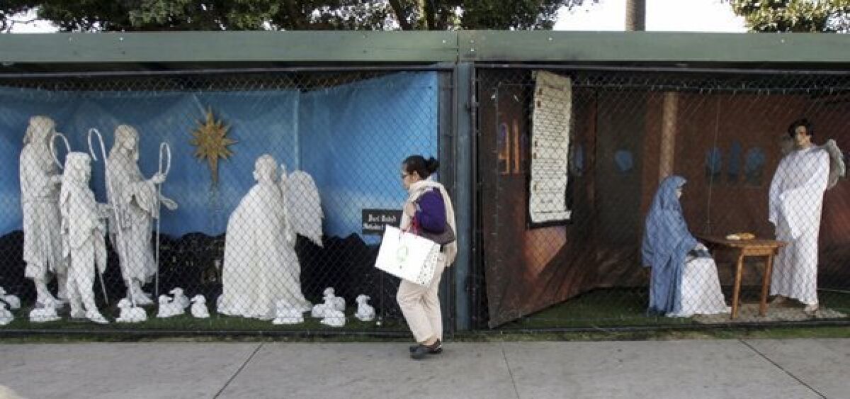 A woman, seen here in December 2011, walks past two of the Nativity displays that for 60 years had been put up in Palisades Park in Santa Monica.