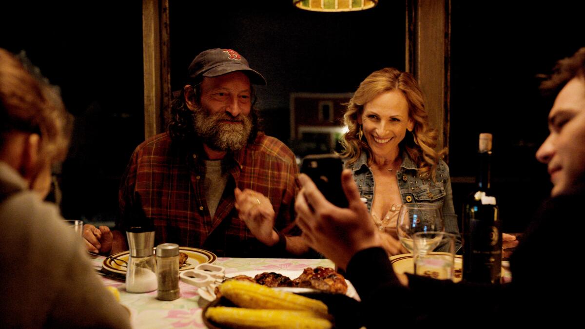 Troy Kotsur, left, and Marlee Matlin sitting at a dinner table