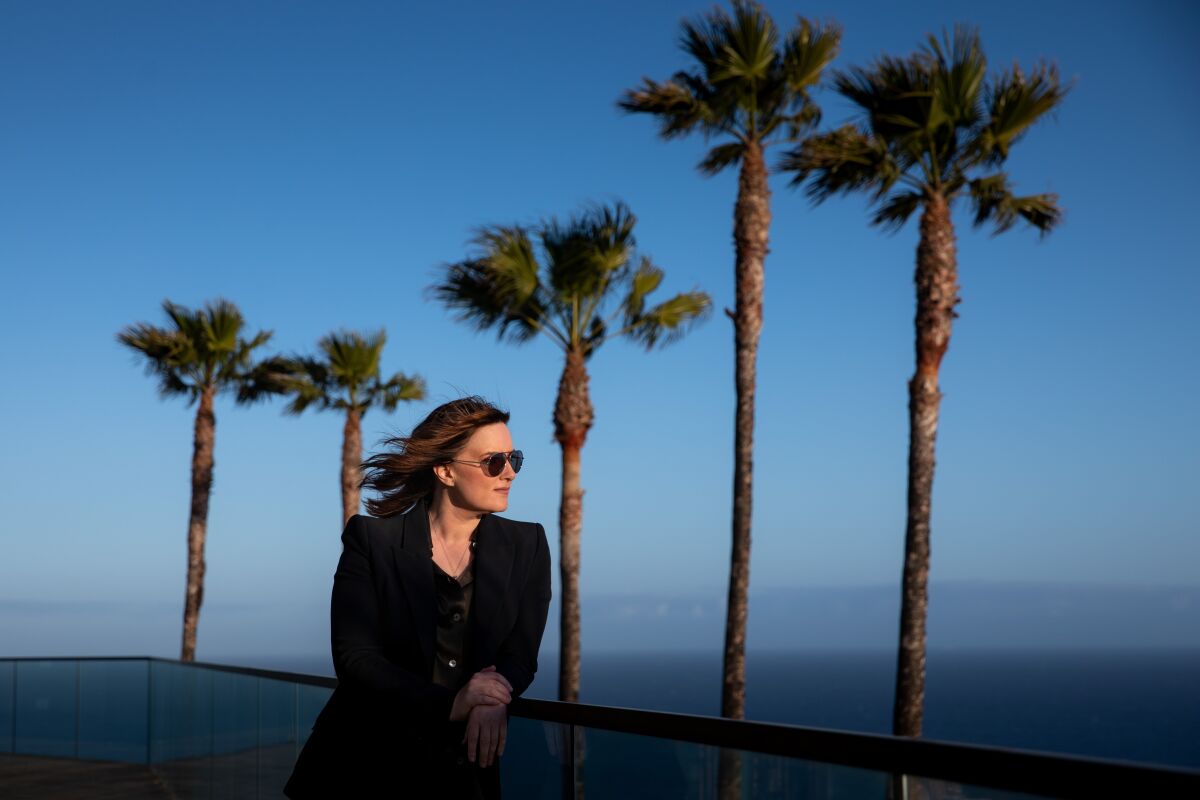 A woman poses for a portrait amid palm trees.