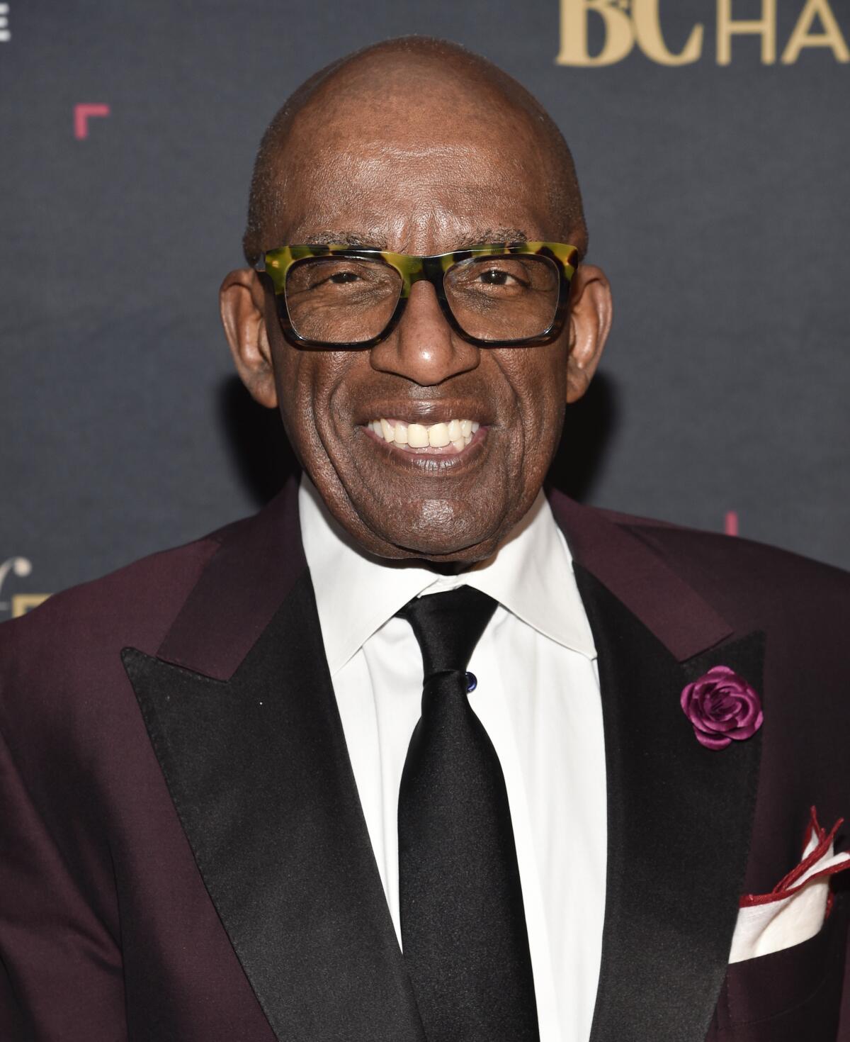 Al Roker smiling in a burgundy suit and tie with a flower on the lapel
