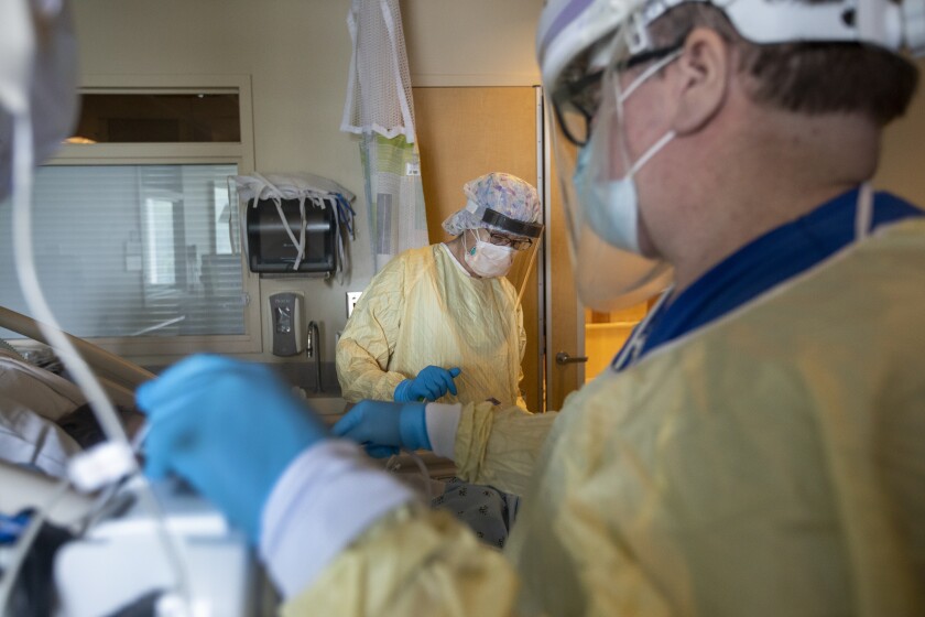 Magda Arredondo, left, and Patrick Sheehy, RN, right, reposition a patient in the ICU 