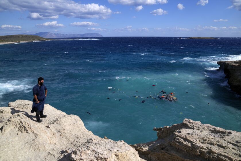 Un residente de la zona se ve de pie en un acantilado mientras se ven cuerpos de varios migrantes entre los restos de un velero que se estrelló contra las rocas y se hundió en la isla de Citera, en el sur de Grecia, el jueves 6 de octubre de 2022. (AP Foto/Thanassis Stavrakis)