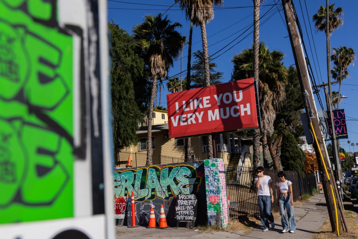 Pedestrians walk past the "I LIKE YOU VERY MUCH" billboard in Silver Lake on Wednesday, May 21, 2025 in Los Angeles, CA.