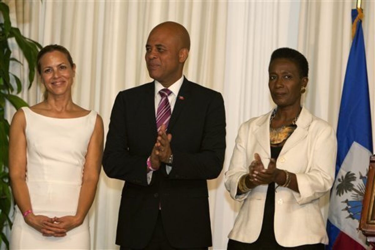 Haiti's President Michel Martelly is flanked by Haiti's new goodwill ambassadors, actress Maria Bello, left, and former government official Danielle Saint Lot at a ceremony in their honor at the National Palace in Port-au-Prince, Haiti, Tuesday, Oct. 23, 2012. Saint Lot is a longtime women’s activist and Bello is the co-founder of women’s grassroots group We Advance. (AP Photo/Dieu Nalio Chery)