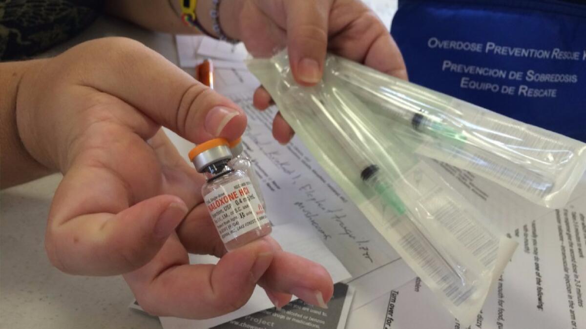 A community health outreach worker holds a vial of naloxone and syringes. The drug can save the life of someone who has overdosed on opioid painkillers.