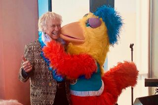 Dion Rich gets a hug and a peck on the cheek from The Famous Chicken during Rich's 90th birthday party Nov. 16 at a high-rise party space overlooking Petco Park.
