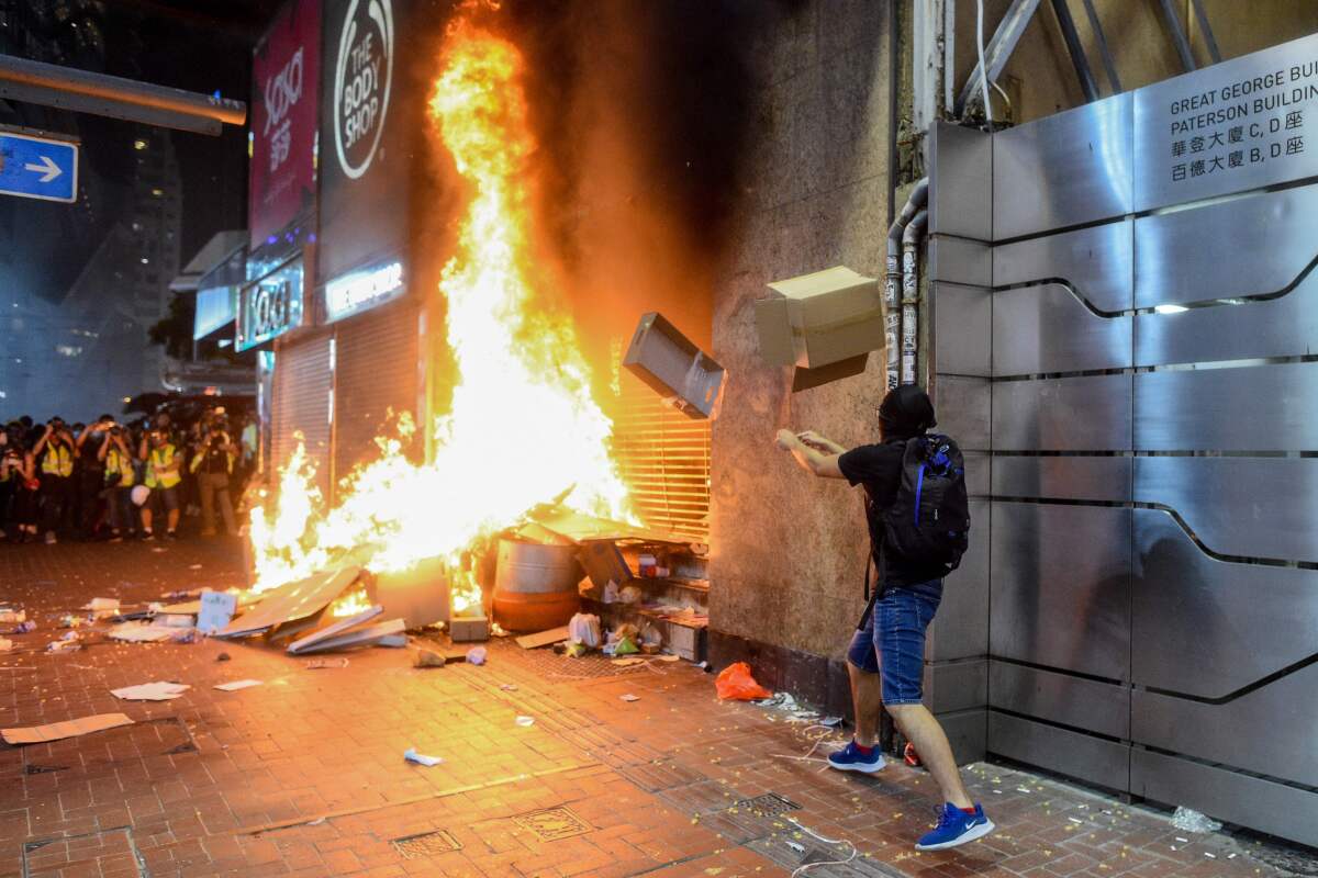 Protesters burn items at the Causeway Bay metro station entrance in Hong Kong, as people hit the streets after the government announced a ban on face masks.