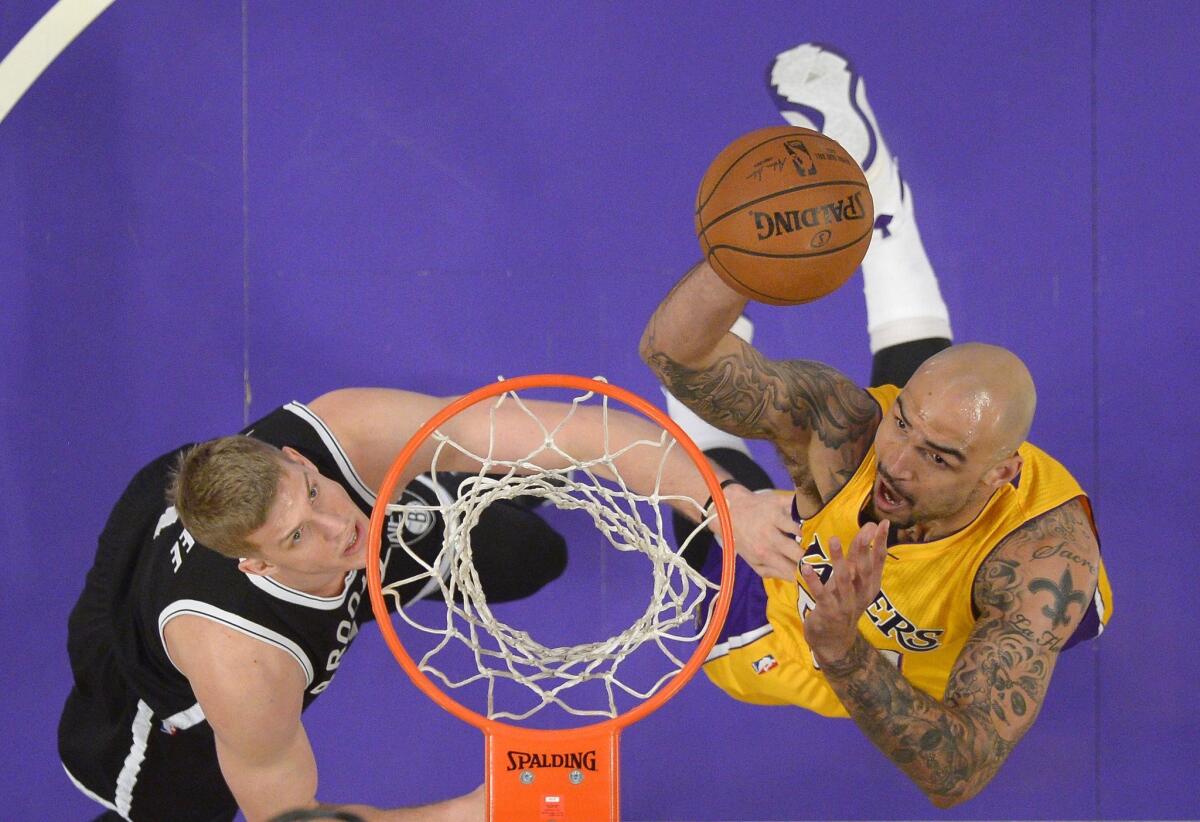 Lakers center Robert Sacre, right, shoots as Brooklyn Nets center Mason Plumlee defends on Feb. 20.