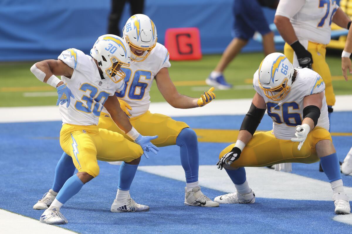 Chargers running back Austin Ekeler (30) celebrates a touchdown run alongside teammates by playing the air guitar.
