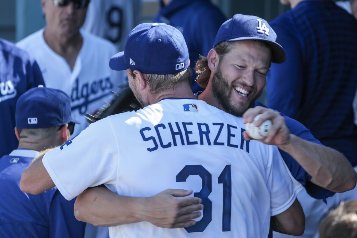 Dodgers starting pitcher Max Scherzer is hugged by teammate Clayton Kershaw in the dugout.