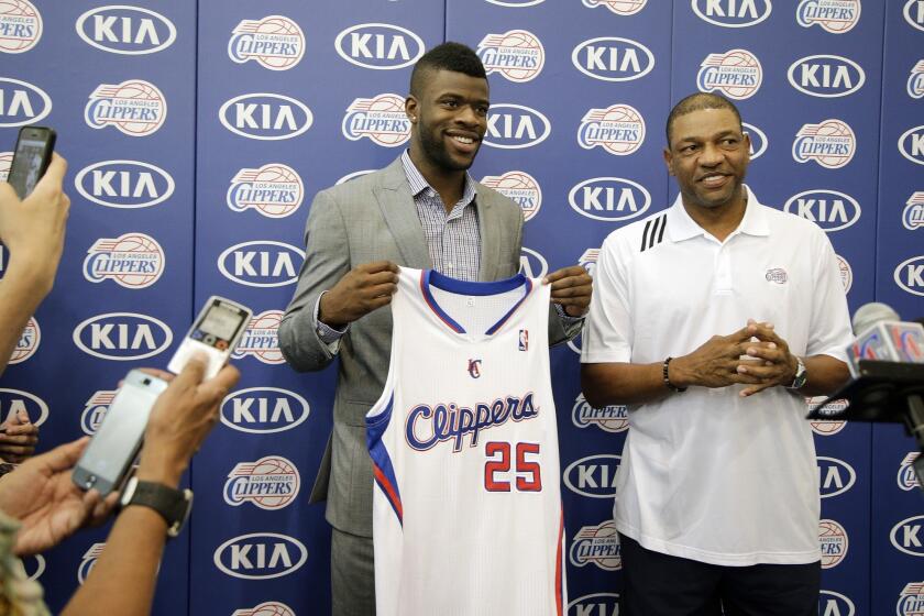 Clippers first-round draft choice Reggie Bullock, left, holds his jersey while posing for photographs with Coach Doc Rivers during a news conference Monday.