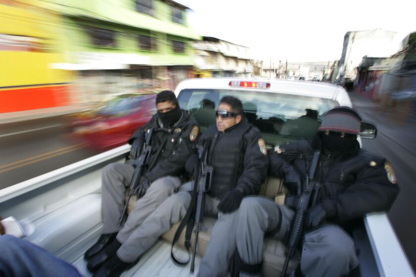 A truck carrying five black-clad Federal Police officers with visible guns blurs through the Zona Norte section of Tijuana  