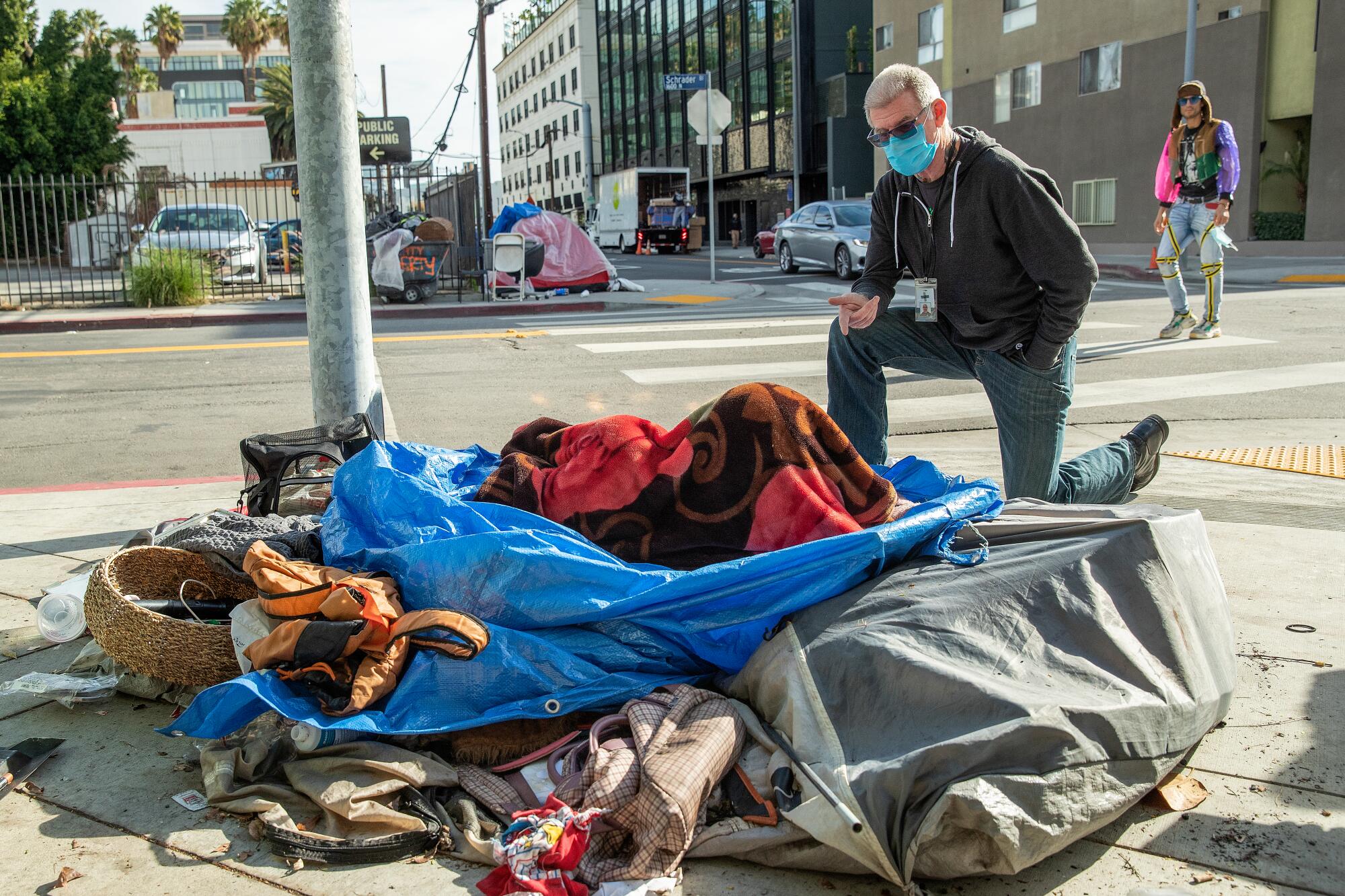Jason Sodenkamp talks to a homeless client on a sidewalk in Hollywood.