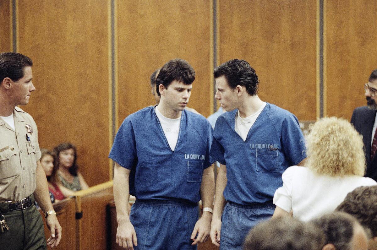 Two men in blue prison uniforms talk as they leave a courtroom.