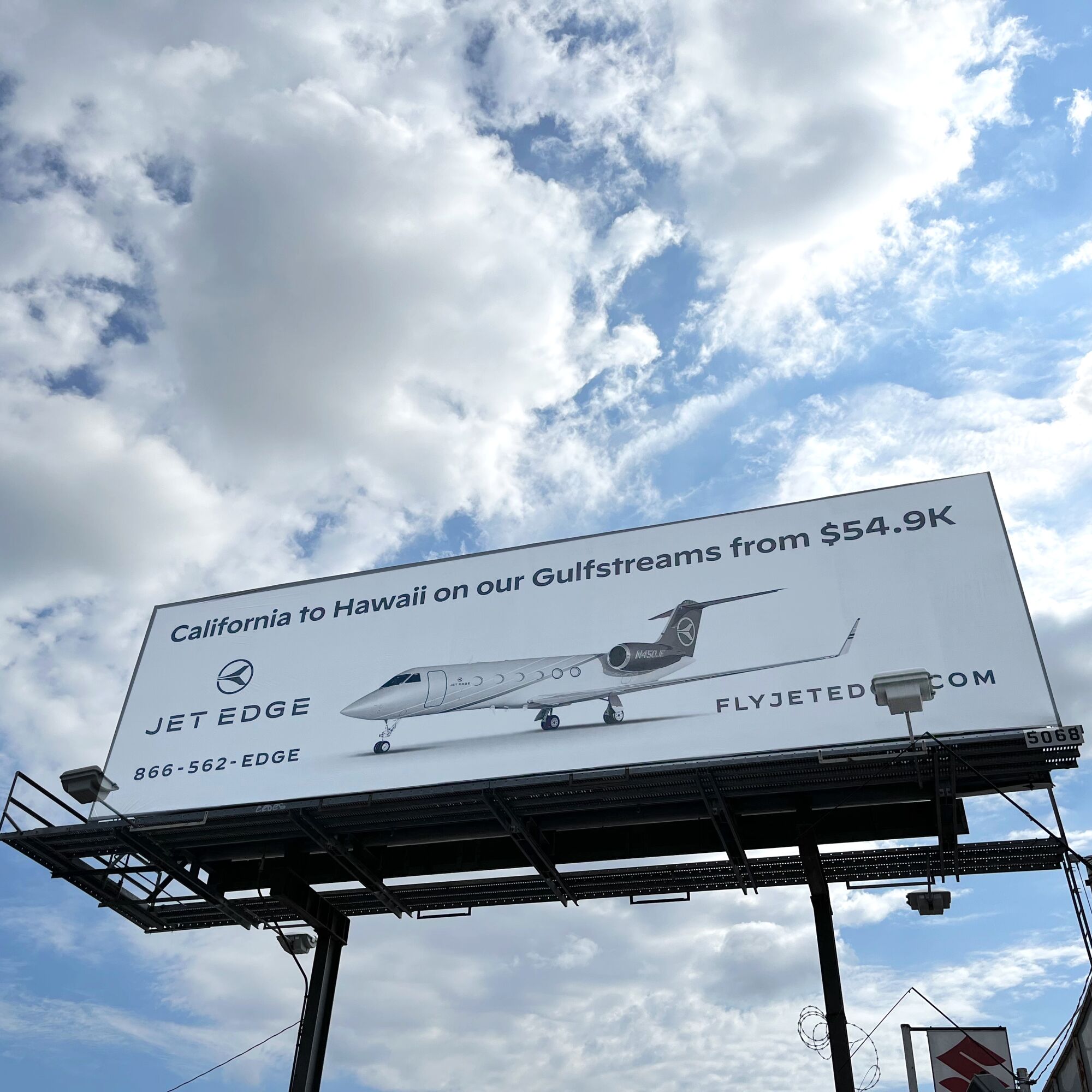 A billboard for Jet Edge advertises a private jet charter on Gulfstream to Hawaii for $54,900.