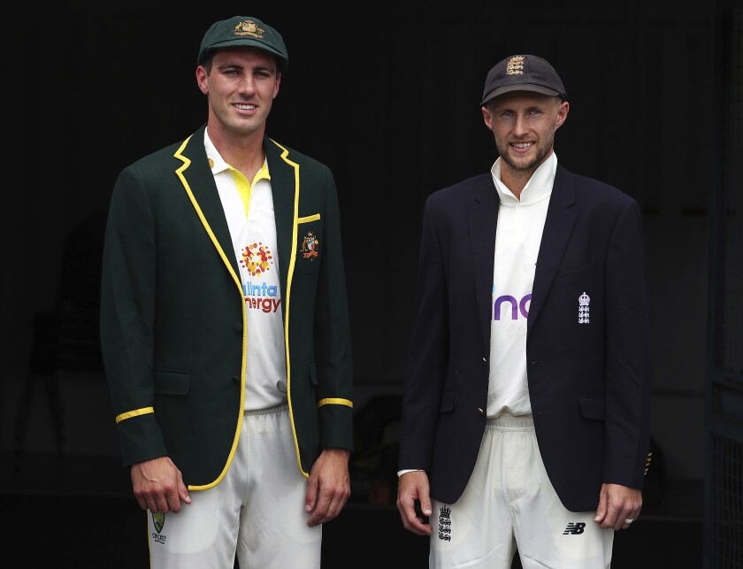 Australian captain Pat Cummins, left, and England captain Joe Root pose for a photo at the Gabba cricket ground ahead of the first Ashes cricket test in Brisbane, Australia, Sunday, Dec. 5, 2021. (AP Photo/Tertius Pickard)