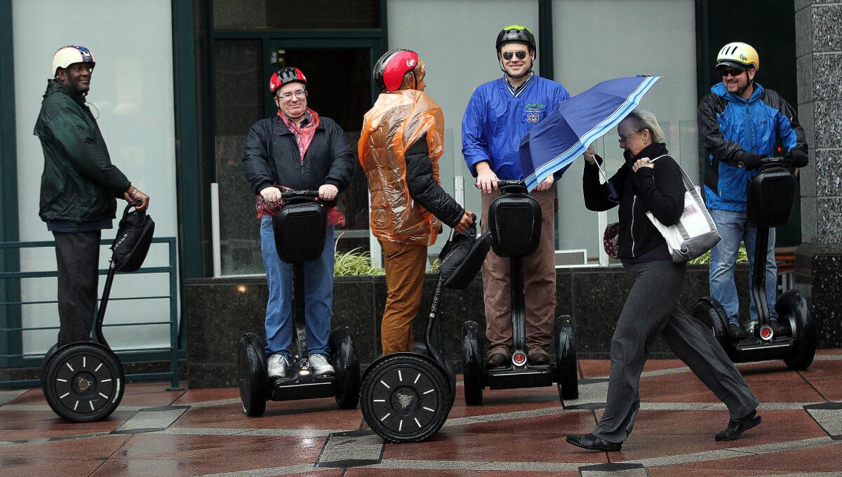 A woman walked past a group on a Segway tour that got caught in the rain downtown on Broadway.