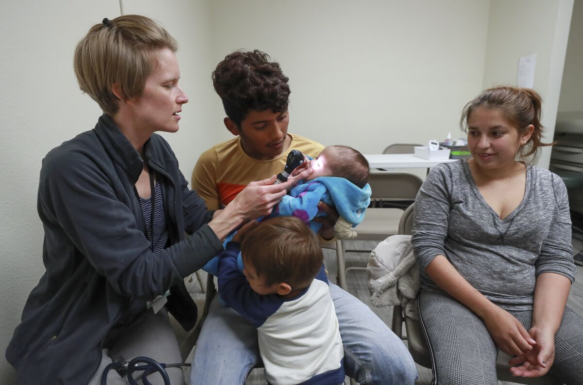 A doctor examines a baby held by parents