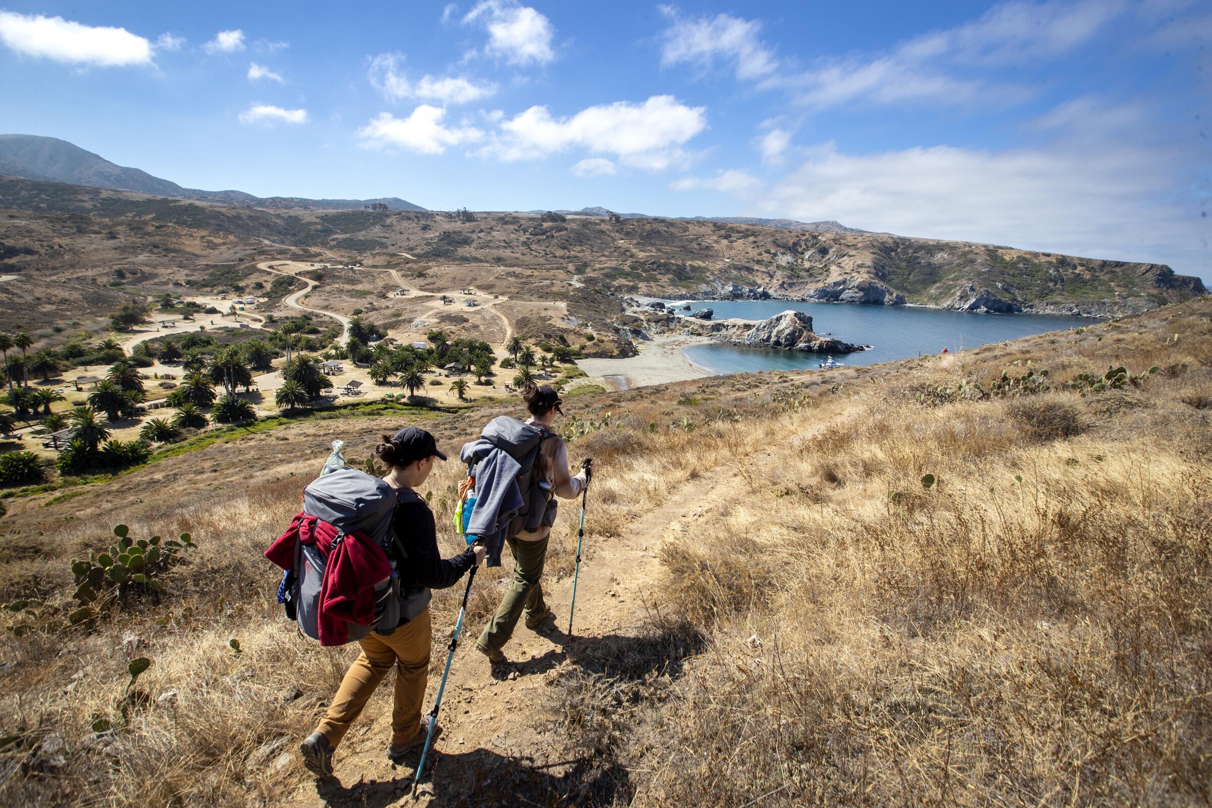 Two hikers, wearing backpacks, arrive at Little Harbor campground.