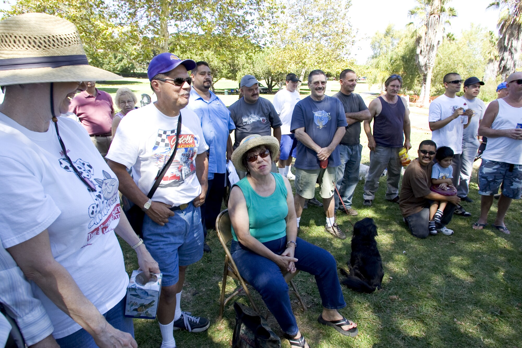 A crowd of people sit and stand on the grass 