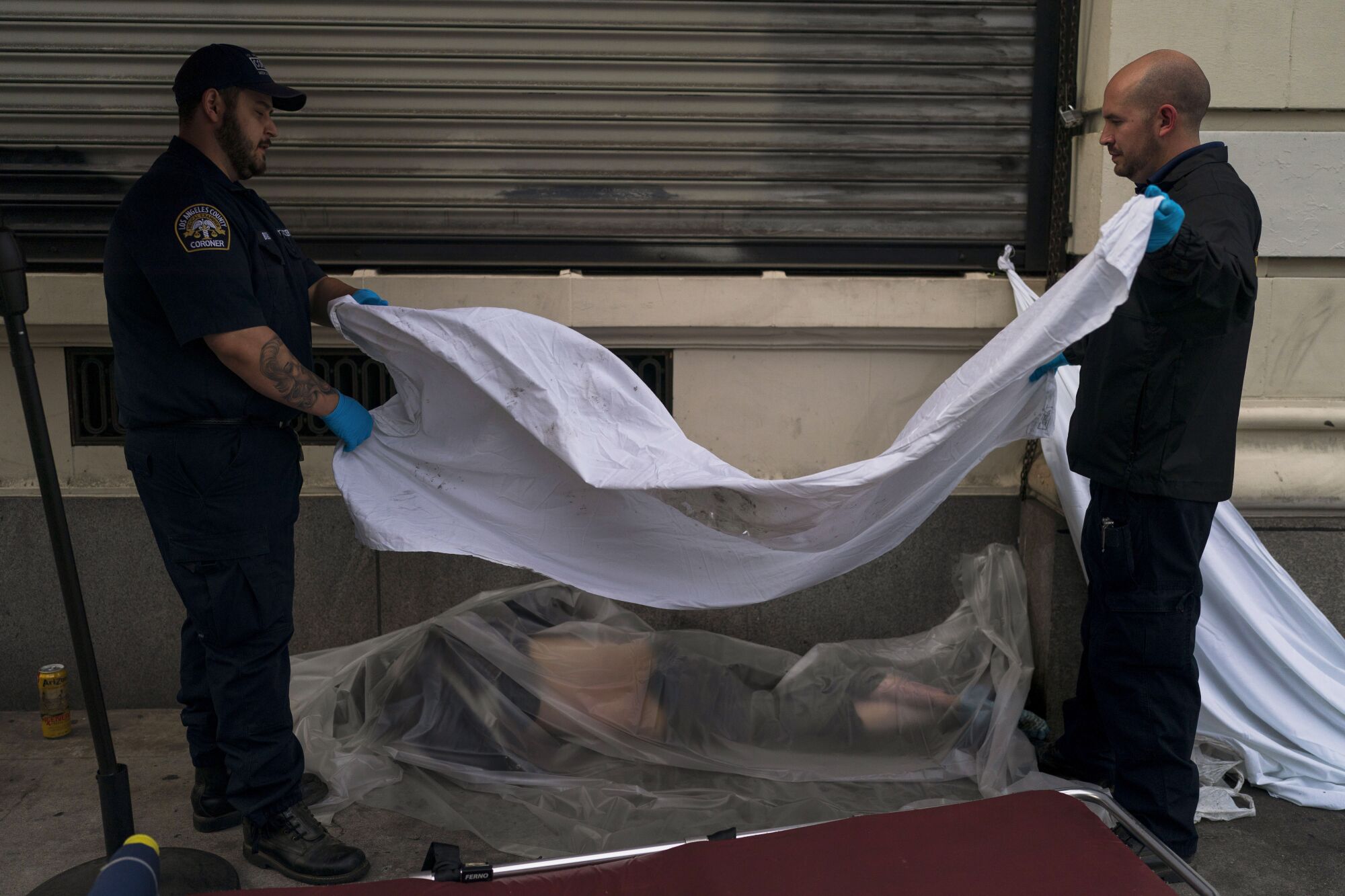 Members of the Los Angeles County coroner's office cover the body of a homeless man found dead on a sidewalk in Los Angeles.