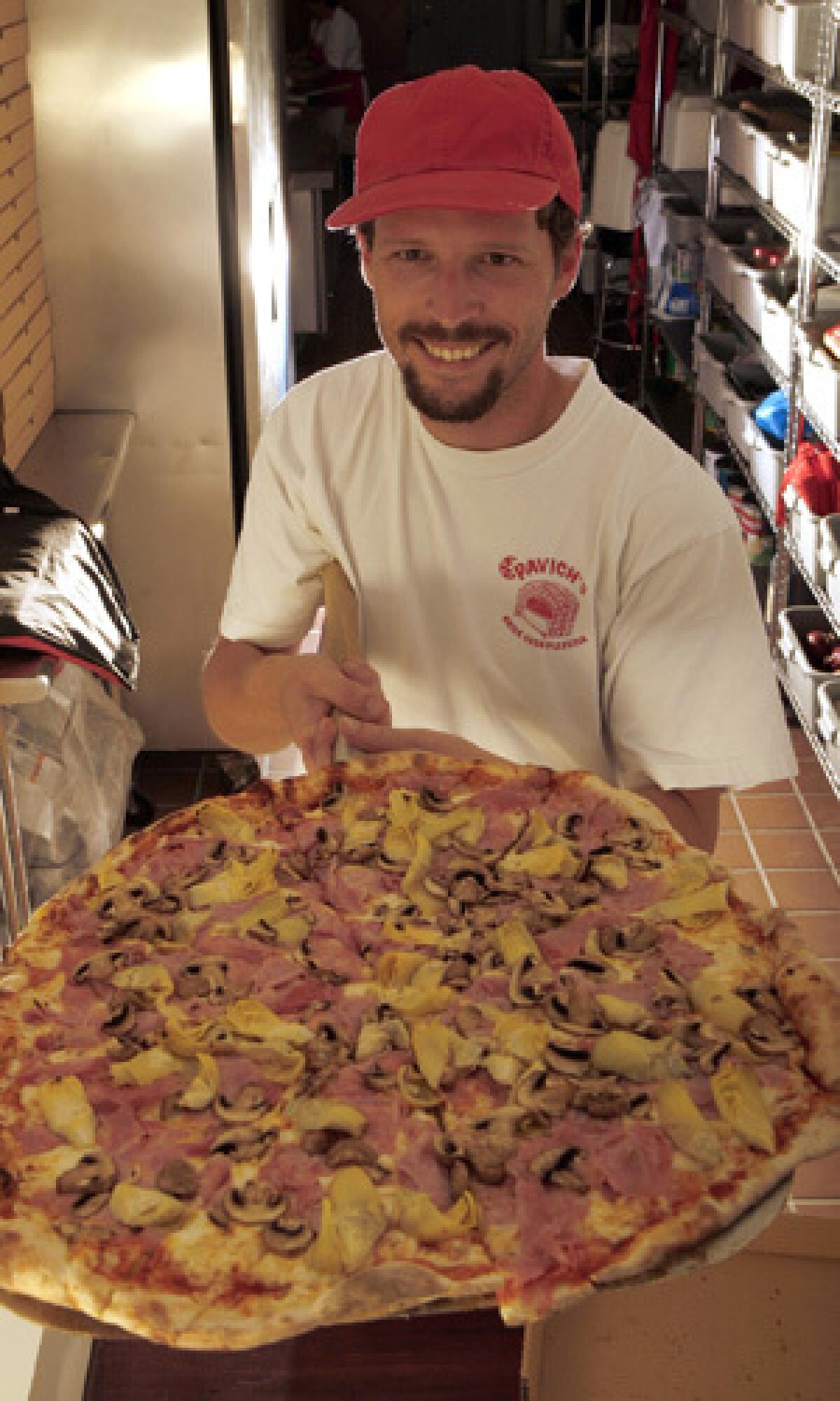 Angelo Vukelja holds an A Quattro Gusti pizza topped with mushrooms, artichokes, ham and cheese at Pavich's Brick Oven Pizzeria in San Pedro.