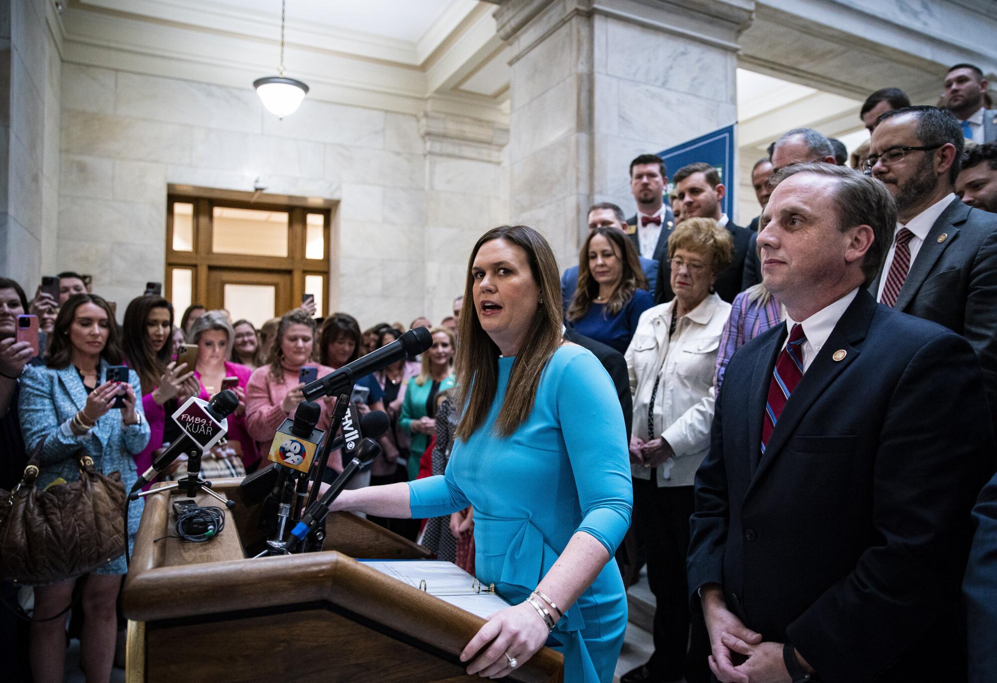 Sarah Huckabee Sanders, governor of Arkansas, speaks at a podium, surrounded by people