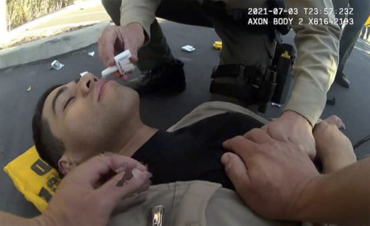 In this image taken from police body camera video and provided by the San Diego County Sheriff's Department, San Diego County Sheriff's Deputy David Faiivae gets aid from an officer, after being exposed to fentanyl on July 3, 2021 in San Diego. A public safety video that told viewers the deputy had a near-death experience after being exposed to fentanyl used the actual footage, the San Diego Sheriff's department said Monday, Aug. 9, 2021, after critics questioned the deputy's severe reaction. The video shows "an actual incident involving the deputy as he processed a white powdery substance that tested positive for Fentanyl," a department news release said. (San Diego County Sheriff's Department via AP)