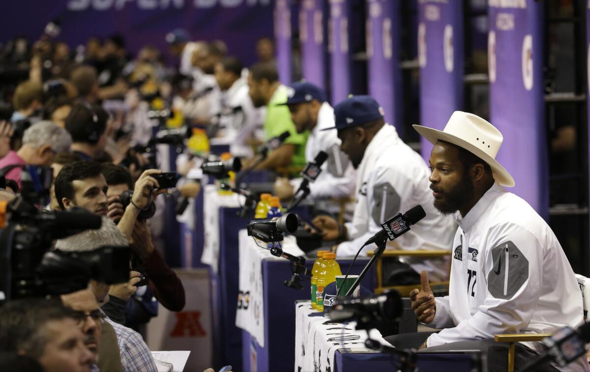 Seattle defensive end Michael Bennett, right, answers questions during the Seahawks' portion of media day Tuesday ahead of Super Bowl XLIX on Sunday at University of Phoenix Stadium in Glendale, Ariz.