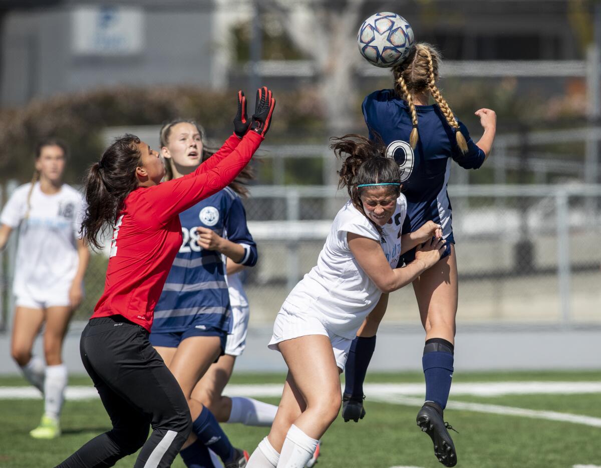 Newport Harbor's Brielle Benedict goes up for a header against Corona del Mar's Madeline Rosen and goalie Sydney Walls.