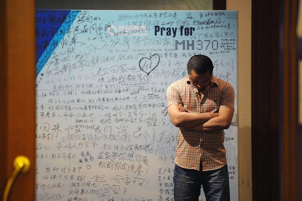 A man stands in front of a billboard in support of missing Malaysia Airlines Flight MH370 as Chinese relatives of passengers on the flight have a meeting at the Metro Park Hotel in Beijing on April 23.