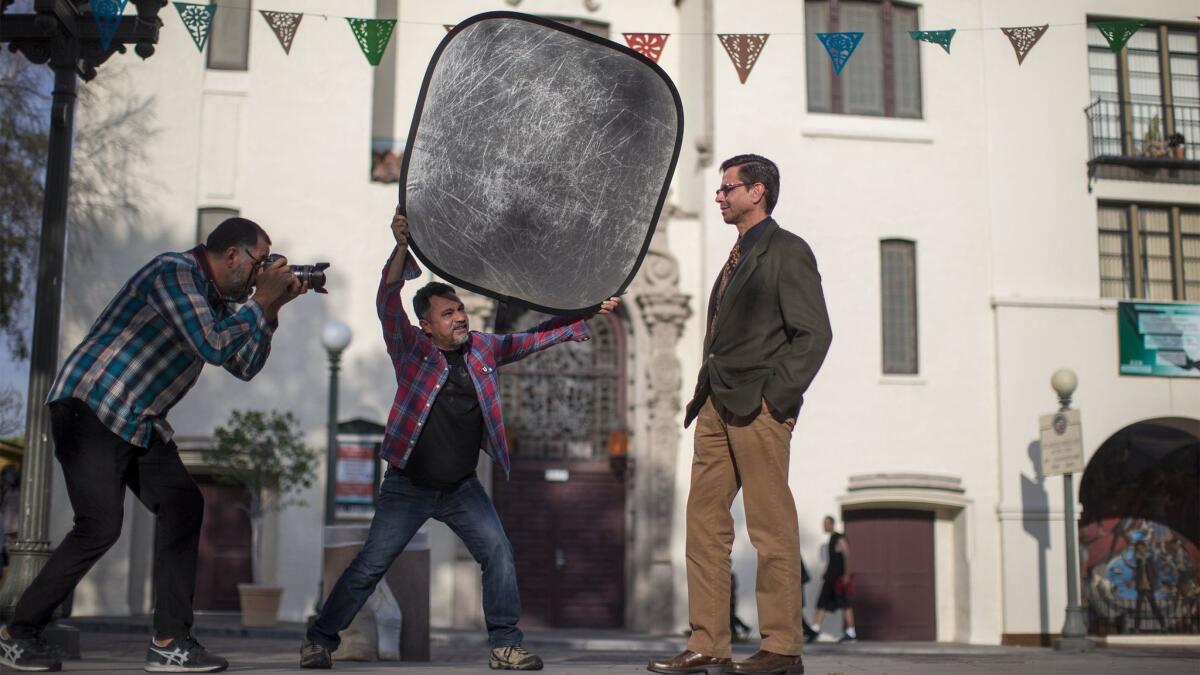 Project photographer Noe Montes, left, photographs Adan Ortega of Fullerton for Miguel Luna's, middle, Power of U project on Feb. 8, 2017, in Los Angeles.