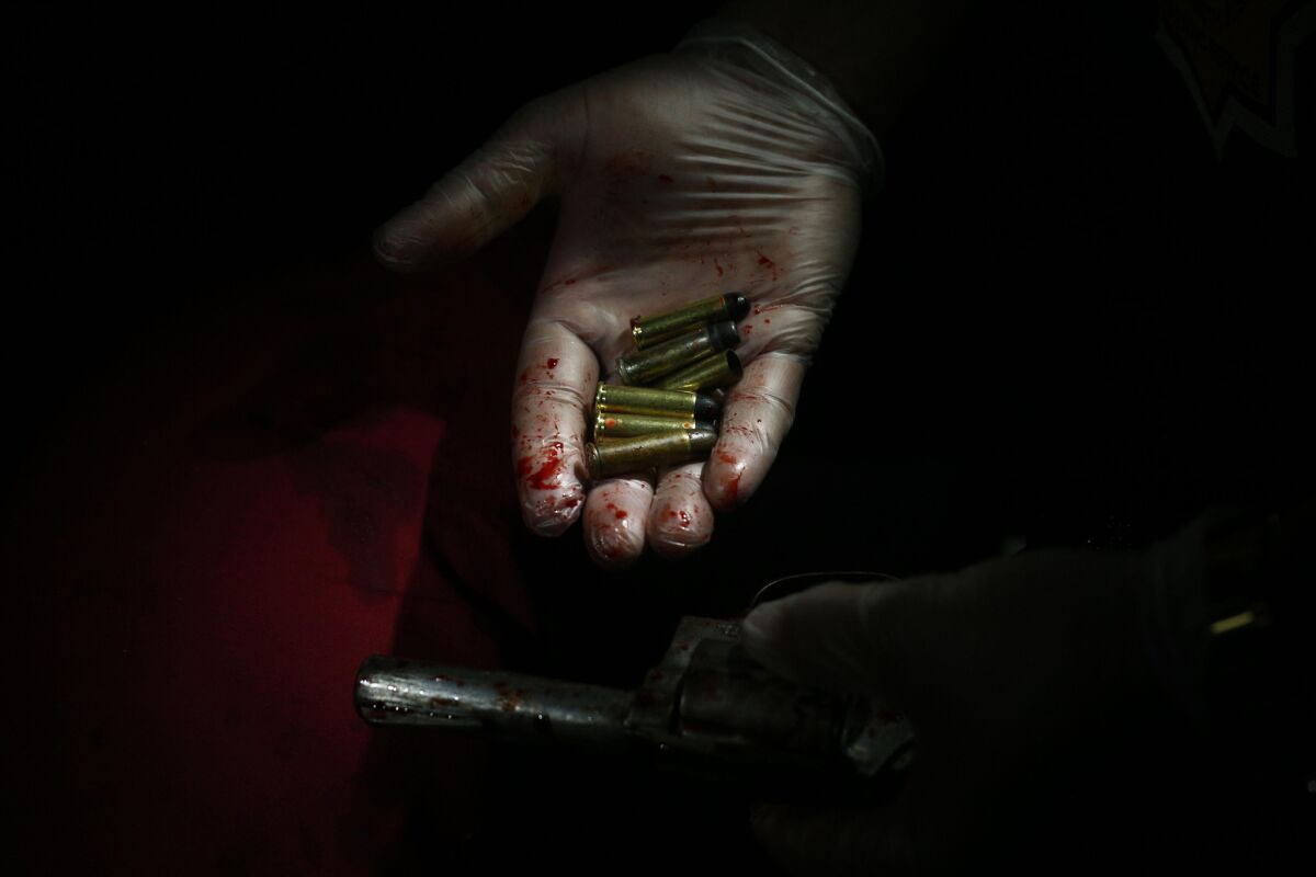 A law enforcement official shows the bullets and a handgun found at a crime scene in Manila.