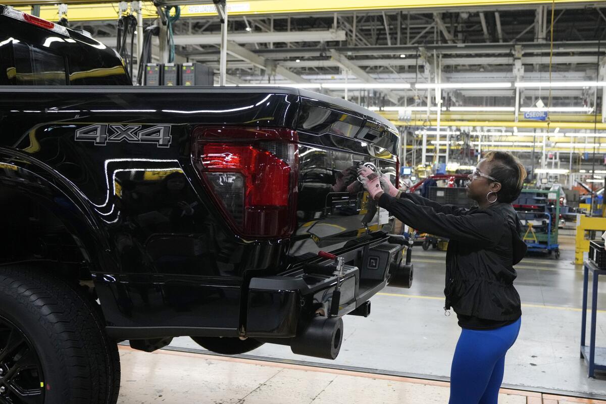 Assembly line worker Lashunta Harris applies the Ford logo on a 2024 Ford F-150 truck being assembled. 