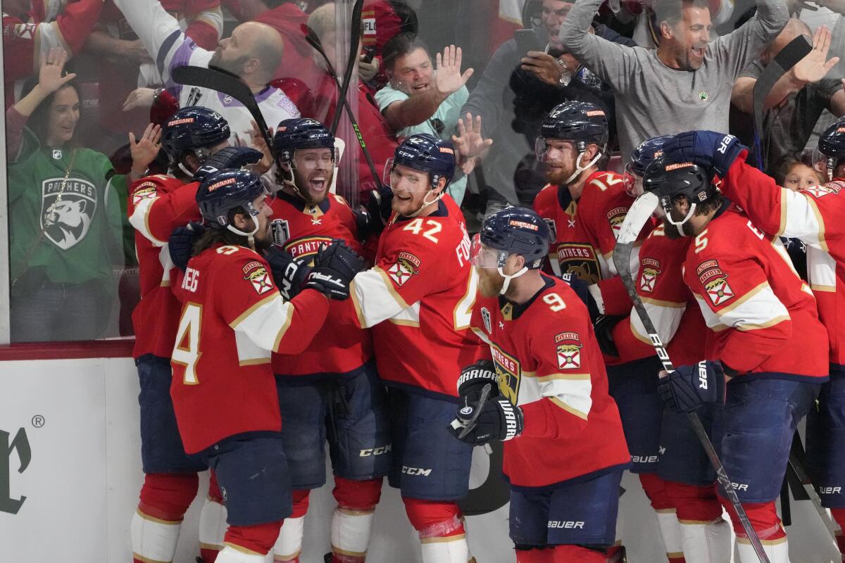 The Florida Panthers team crowd around center Carter Verhaeghe after he scored the game-winning goal in overtime.