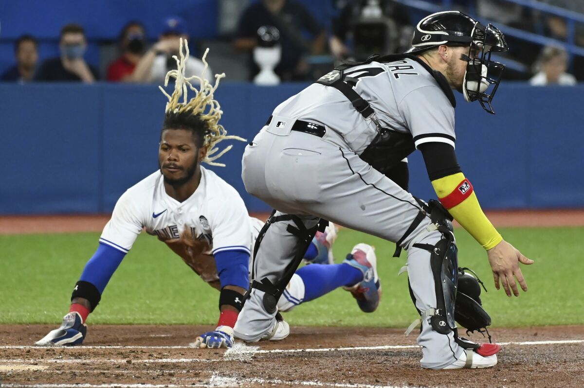 Toronto Blue Jays' Raimel Tapia, left, slides safely into home ahead of a tag by Chicago White Sox catcher Yasmani Grandal, right, on a double by Santiago Espinal in the fifth inning of a baseball game in Toronto, Thursday, June 2, 2022. (Jon Blacker/The Canadian Press via AP)