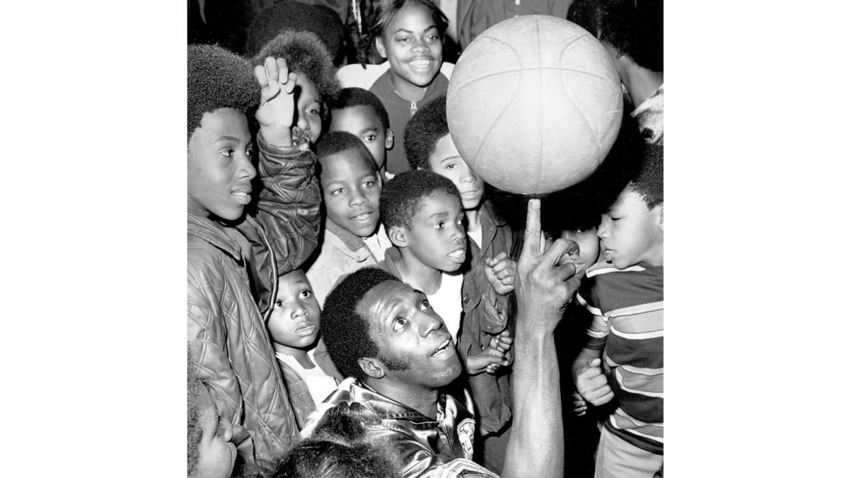 Meadowlark Lemon demonstrates ball twirling to a group of Los Angeles youngsters in 1972. Lemon's blend of slapstick humor and basketball skills brought joy to millions of fans around the world,